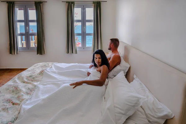 Koppel in wit bed met uitzicht op de oceaan tijdens luxe vakantie in Griekenland — Stockfoto