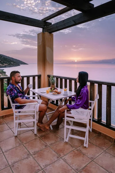 Mesa y sillas con desayuno durante el amanecer en el mar meditario en Grecia —  Fotos de Stock