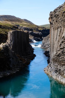 Studlagil Kanyonu 'nun nefes kesen güzelliğini tecrübe edin. İzlanda' da yükselen bazalt sütunlar arasında yoğun mavi suların aktığı yer.
