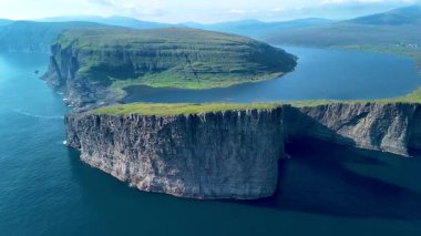 Faroe Adaları 'nın sakin sularından, yemyeşil manzaralar ve nefes kesici manzaralarla çevrili dramatik uçurumlar görkemli bir şekilde yükselir. Sorvagsvatn Gölü, Vagar