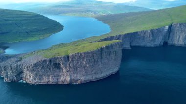 Uçurumlar sakin suların üzerinde görkemli bir şekilde yükselirken Faroe Adaları 'nın dramatik manzarasını deneyimleyin. Sorvagsvatn Gölü, Vagar
