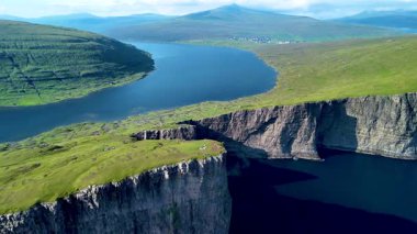 Sakin mavi suların üzerinde yükselen sarp kayalıklarıyla Faroe Adalarının nefes kesici güzelliği. Bu görkemli manzara yemyeşil ve uzak dağları barındırır. Sorvagsvatn Gölü, Vagar