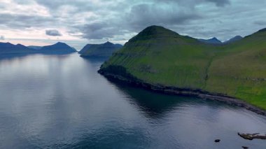 Tjornuvik 'in nefes kesici güzelliğini keşfedin, dramatik uçurumlar ve kasvetli bir gökyüzünün altındaki sakin sular. Alacakaranlıkta doğanın huzurunu yakalamak için mükemmel bir yer..