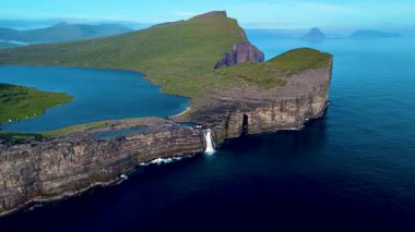 Faroe Adaları 'nın doğal güzelliklerini dramatik uçurumlar ve çağlayan bir şelaleyle keşfedin. Altın saatinde yemyeşil ve sakin kıyı manzarasının tadını çıkar. Sorvagsvatn Gölü