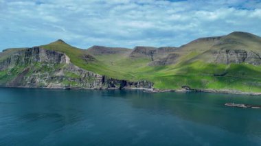 Faroe Adaları 'nın nefes kesici uçurumlarını ve sakin sularını keşfedin. Canlı yeşil tepeler sakin denizin üzerinde dramatik bir şekilde yükseliyor, bu uzak varış noktasının çarpıcı manzarasını gözler önüne seriyor..