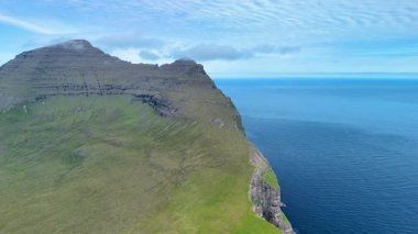 Büyük yeşil manzaralar Atlantik Okyanusu 'ndan dramatik bir şekilde yükseliyor ve Faroe Adaları' nın büyüleyici sahil kayalıklarını gözler önüne seriyor. Bu nefes kesici bakış açısı doğanın güzelliğini vurgular..