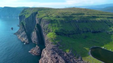 Yüksek uçurumların nefes kesici manzarası Faroe Adaları 'nda sakin sularla buluşuyor. Bu uzak cenneti karakterize eden dramatik manzaraları ve bereketli yeşilliği tecrübe edin..