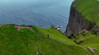 Faroe Adaları 'ndaki Kalsoy Adası' ndaki çarpıcı yeşil manzaralar ve dramatik deniz uçurumları. Nefes kesen okyanus manzarası ve engebeli tepelere giden huzurlu yürüyüş yollarının tadını çıkar..