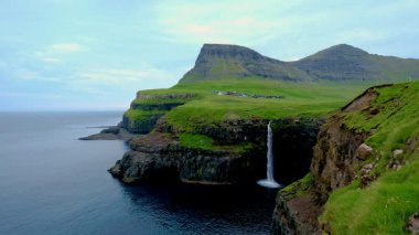 Nefes kesici Faroe Adaları 'ndaki Gasadalur yakınlarındaki Atlantik Okyanusu' na zarif bir şekilde yuvarlanan çarpıcı Mullafossur Şelalesine tanık olun. Doğal güzellik her yöne doğru açılır..