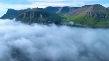 Göz kamaştırıcı Faroe Adaları gökyüzüne hakim olurken yoğun sis yemyeşil tepeleri kaplarken şafak vakti büyüleyici bir doğal manzara yaratıyor..
