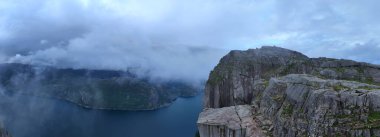 Nefes kesici Preikestolen Uçurumu Lysefjorden 'ın dingin sularının üzerinde çarpıcı bir şekilde yükseliyor, büyüleyici doğal güzellikle çevrili ve sisle örtülü. Macera arayanlar için mükemmel bir yer..