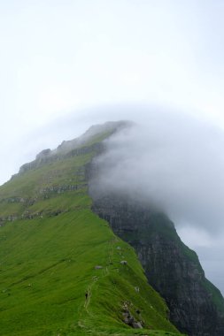 Faroe Adaları 'ndaki bu çarpıcı uçurum esrarengiz bir sis bulutuyla kaplanmış manzaradan çarpıcı bir şekilde yükseliyor. Kallur Deniz Feneri, Kalsoy Adası