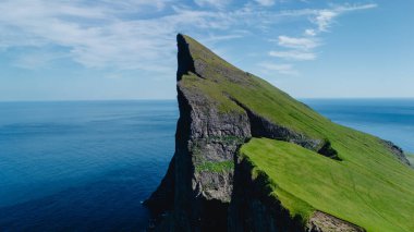 Yükselen deniz kayalıkları Faroe Adaları 'ndaki derin mavi okyanusun üzerinde görkemli bir şekilde yükselerek yemyeşil ve çarpıcı doğal güzellikleri gözler önüne seriyor. Doğa aşıkları ve maceracılar için mükemmel bir yer..
