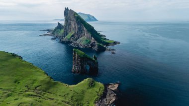 Faroe Adaları 'nın dramatik Drangarnir uçurumlarına ve canlı yeşilliklerine bakan bu nefes kesici manzara doğanın dingin güzelliğini yakalar..
