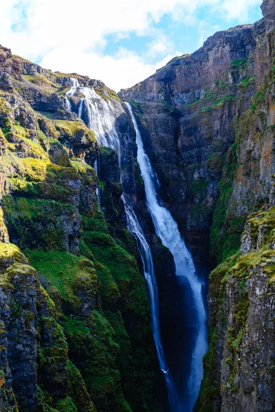 Parlak yeşillik ve dramatik kaya oluşumlarıyla çevrili İzlanda 'daki sarp kayalıklardan çarpıcı bir şelale devriliyor. Glymur şelalesi