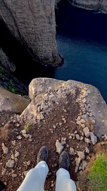 Faroe Adaları 'ndaki kayalık bir uçurumun kenarında duran manzara derin mavi bir okyanusu ve dramatik kaya oluşumlarını gözler önüne seriyor. Doğanın özünü yakalar saf güzellik, Sorvagsvatn Gölü, Vagar