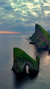 Çarpıcı kaya oluşumlarıyla karakterize edilmiş dramatik Drangarnir uçurumlarına tanık olun. Faroe Adaları 'nın sakin deniz sularının üzerinde gururla duruyorlar..