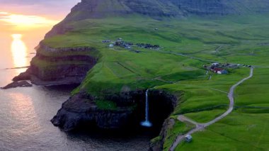 Derin nefes kesici Mullafossur Şelalesi 'ni keşfedin. Etrafı yemyeşil tepelerle ve Gasadalur' un büyüleyici köyüyle çevrili okyanusa dökülen şelalenin altın gün batımının tadını çıkarın..