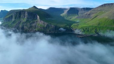 Faroe Adaları 'nın nefes kesen uçurumlarını ve sakin sularını keşfedin. Sisli kıyıların üzerinde dramatik kaya oluşumları gün boyunca büyüleyici ve sakin bir atmosfer oluşturur..