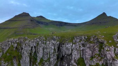 Alacakaranlıkta Faroe Adaları 'ndaki Gjogv' un nefes kesen uçurumlarını keşfedin. Yeşilliğin engebeli kaya oluşumlarıyla buluştuğu yerleri. Huzurlu güzellik doğanın ihtişamına macera ve yansımayı davet eder..