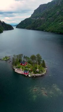 Huzurlu sularda, Lovrafjorden Norveç 'teki küçük bir adada canlı kırmızı bir kulübe duruyor..