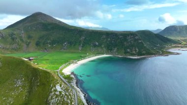 Soluk kesici hava perspektifi Norveç 'in Lofoten kentindeki Haukland plajına bakan Mannen Dağı' nı gösteriyor. Berrak turkuaz sular, yemyeşil araziyle çevrili kumlu sahili öper..