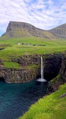 Faroe Adaları 'ndaki Gasadalur' un yemyeşil manzaralarıyla çevrili aşağıdaki turkuaz sulara doğru dramatik uçurumlara dökülen Mullafossur Şelalesi 'nin çarpıcı güzelliğini deneyimleyin..