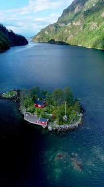Huzurlu bir fiyortta, görkemli dağlar ve sakin sularla çerçevelenmiş yemyeşil bir adada canlı kırmızı bir kulübe duruyor. Lovrafjorden Norveç 'in huzurunu ve güzelliğini arayan doğa severler için ideal.