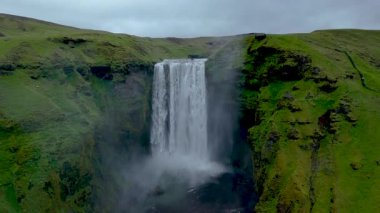 Skogafoss 'tan zarif bir şekilde akan su İzlanda' nın canlı yeşil tepeleri arasında sisli bir ortam yaratıyor. Doğa tüm ihtişamıyla bu ikonik konumun güzelliğini gözler önüne seriyor..