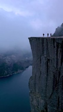 Yürüyüşçüler Norveç 'te Preikestolen' in kıyısında durup nefes kesici manzaranın tadını çıkarıyorlar..