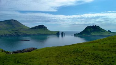 Faroe Adaları 'nın nefes kesen güzelliğini keşfedin. Parlak mavi bir gökyüzünün altındaki sakin sulardan yükselen sarp kayalıkları keşfedin. Doğa meraklıları ve gezginleri için mükemmel..