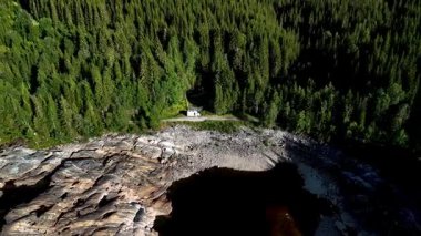 Kayalık kıyı şeridinin ortasında canlı yeşilliklerle çevrili büyüleyici bir karavan oturuyor. Norveç 'teki bu sakin yer, yükselen ağaçlar ve köpüklü suyla doğanın güzelliğini gözler önüne seriyor.
