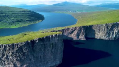 Bereketli yeşil manzaraların engebeli kıyılarla buluştuğu Faroe Adaları 'nın nefes kesici uçurumlarını ve sakin sularını keşfedin. Sabahın erken saatlerinde sakin denize çarpıcı yansımalar gelir..