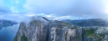 Yüksek uçurumların Lysefjord 'un dingin sularıyla buluştuğu Preikestolen Cliff' ten nefes kesici manzarayı izleyin. Bulutlar sürükleniyor ve bu büyüleyici Norveç manzarasına mistik bir dokunuş ekliyor..