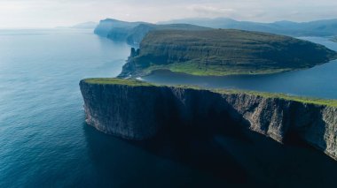 Yüksek uçurumlar, Faroe Adaları 'ndaki sakin deniz sularını görkemli bir şekilde gözden kaçırır. Engebeli arazi dramatik kaya oluşumlarını gözler önüne seriyor, nefes kesen bir ortamda keşif ve macera yaratıyor..