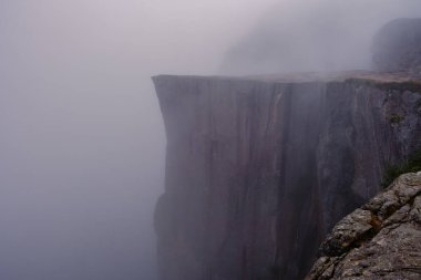 Norveç 'teki Preikestolen Cliff' in nefes kesici manzarasını deneyin, dramatik kaya oluşumunun manzarayı kaplayan ruhani sisle buluştuğu yer. Huzurlu atmosfer keşfi davet ediyor..