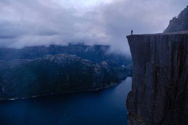 Yalnız bir yürüyüşçü Preikestolen Cliff 'in kenarında duruyor, göz kamaştırıcı Lysefjord' a bakıyor..