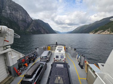 Lysefjord, Norveç, 27 Temmuz 2025, Lysebotn 'dan bir feribot sakin sularda süzülüyor. Görkemli kayalıklar kasvetli bir gökyüzünün altındaki sakin manzarayı çerçeveliyor., 