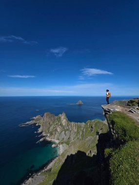 Matind Dağı 'nın zirvesinden çarpıcı panoramik manzara, Andoya, Bleik' te engebeli uçurumlar ve okyanus manzaraları sergiliyor. Parlak yeşil manzara gök mavisi denizle çok güzel tezat oluşturuyor..
