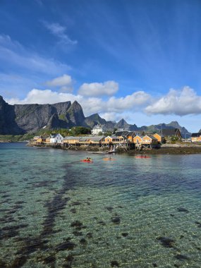 Berrak sular boyunca geleneksel sarı ahşap evlere sahip canlı Sakrisoy köyü. Kayakçılar, çarpıcı mavi gökyüzünün altındaki sakin koyu keşfedip, huzurlu bir kıyı atmosferi yaratıyorlar..