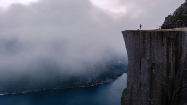 Büyüleyici Lysefjord 'un üzerinde dramatik uçurumlar yükseliyor, Norveç' teki Preikestolen Cliff 'in üzerinde tek başına duran bir figür