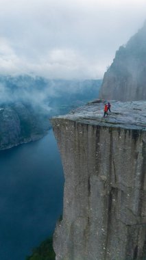 Bir yürüyüşçü zaferle Preikestolen Cliff 'in kenarında duruyor, Norveç' teki göz kamaştırıcı Lysefjord 'a bakıyor..