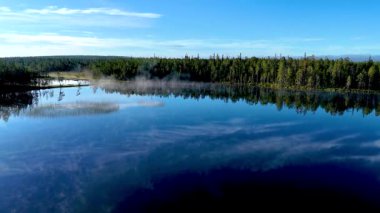 Hossa Ulusal Parkı 'ndaki bir göl, kristal berrak sularıyla Finlandiya' daki yemyeşil ormanları ve dingin gökyüzünü yansıtır.