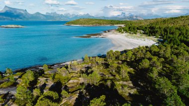 Bognes, Lofoten, Norveç 'te kumlu plajlar, yemyeşil yemyeşil ve açık bir gökyüzü altında uzak dağların bulunduğu el değmemiş kıyı manzarası nefes kesici. Doğa aşıkları ve macera arayanlar için mükemmel..
