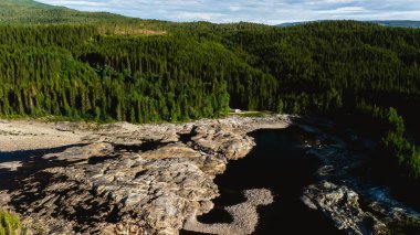 Norveç ormanlarının yemyeşil yeşilliğini sergiliyor. Kayalık oluşumlar ve manzarada akan sakin bir nehir. Doğa aşıkları ve macera arayanlar için mükemmel..