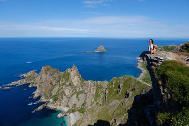 Norveç, Andoya 'daki Matind Dağı' ndan çarpıcı manzarayı izleyin. Yalnız bir yürüyüşçü dramatik uçurumların ve aşağıdaki parıldayan mavi okyanusun el değmemiş manzarasının tadını çıkarır..
