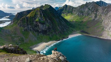 Macera avcıları Ryten 'ın tepesindeki Kvalvika Sahili' ne bakan büyüleyici panoramik manzaraya hayran kalırlar. Canlı yeşil dağlar turkuaz sularla buluşarak Norveç 'te pitoresk bir manzara yaratıyor..
