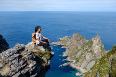 Yalnız bir maceracı, Matind Dağı 'nın kayalık yamacına tünemiş Bleik, Andoya' nın çarpıcı sahil manzarasının tadını çıkarıyor..