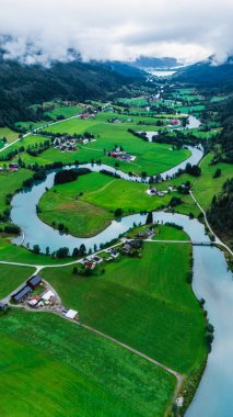 Yeşillik, Norveç 'te Stryn' in manzarasını örtüyor. Nehirler zarif bir şekilde vadiden geçiyor. Tuhaf çiftlik evleri bulutlu bir gökyüzünün yumuşak ışığı altında araziyi benekler..