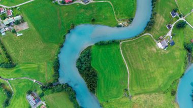 Stryn 'deki dolambaçlı nehrin canlı yeşil tarlalarda ve büyüleyici Norveç kırsallarında akarken nefes kesici manzarası bölgenin çarpıcı doğal güzelliğini gözler önüne seriyor..